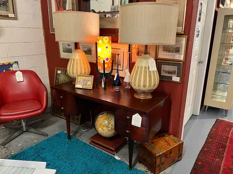 Mid-century desk with a pair of table lamps and a red chair at Picker Joe's Antique Mall in Savannah, GA