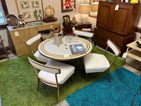 Round dining table with white mid-century chairs on green and teal rugs at Picker Joe's Antique Mall in Savannah, GA
