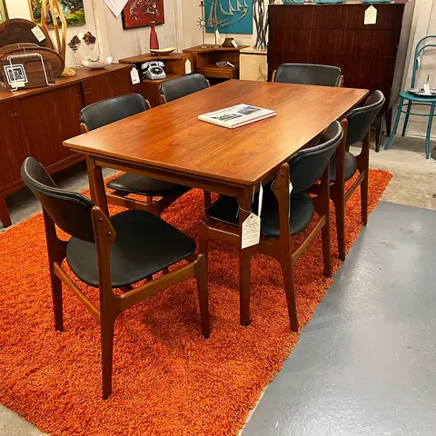 Wood dining table with black mid-century chairs on an orange rug at Picker Joe's Antique Mall in Savannah, GA