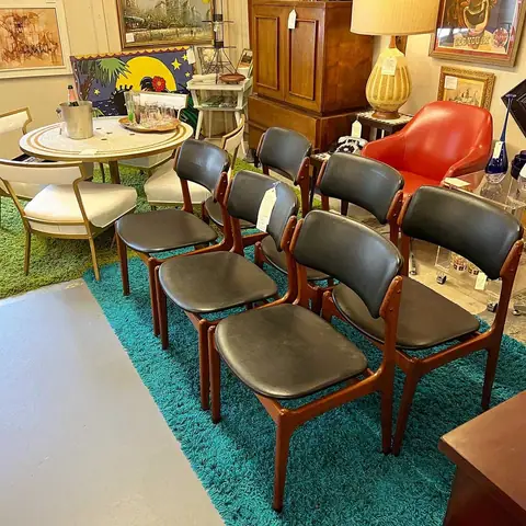 Row of black mid-century dining chairs on a teal rug at Picker Joe's Antique Mall in Savannah, GA